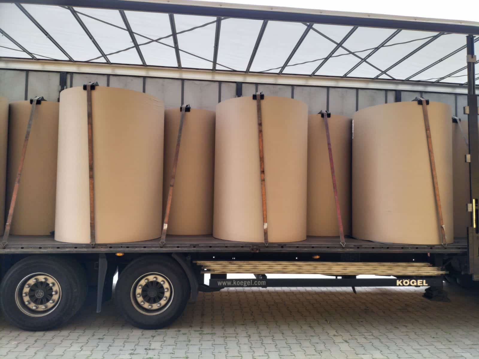 rolki papieru ustawione pionowo na naczepie plandekowej, zabezpieczone pasami